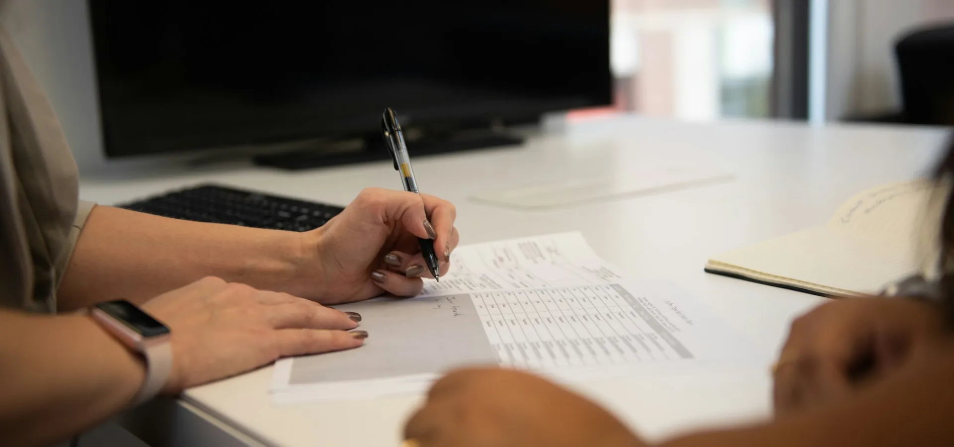 Handwritten paper sign-in sheets and logbooks on a reception desk showing manual member tracking